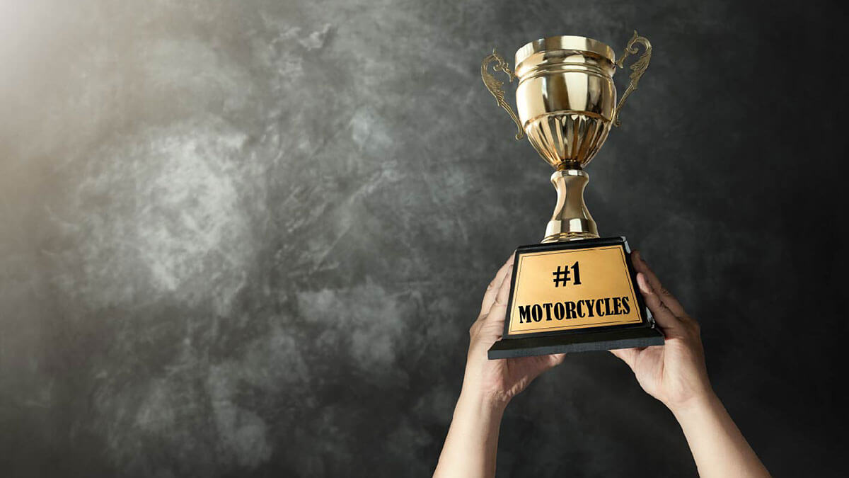 A close-up of hands holding up a trophy with the plaque saying #1 Motorcycles