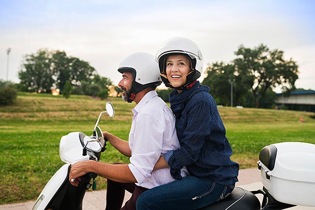 A couple enjoying the sights and sounds while riding on a scooter